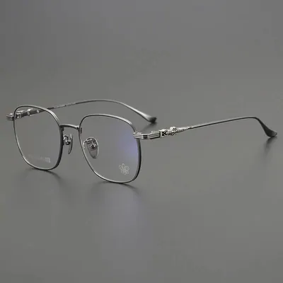 Clear framed glasses with thin metal arms on a grey surface