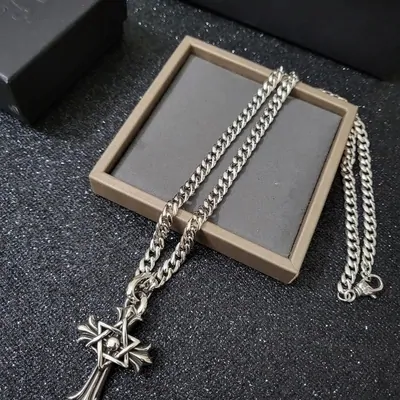A silver chain necklace with a cross pendant, displayed in a frame