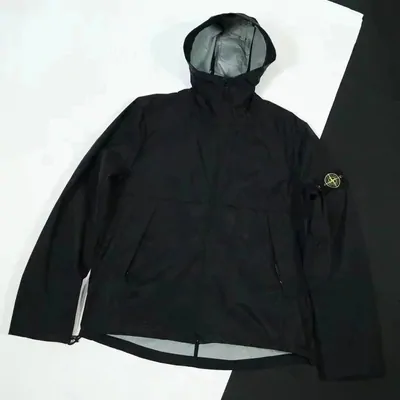 A black hooded technical jacket laid flat with the zip closed