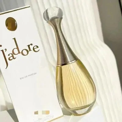 A gold perfume bottle standing beside its ribbed cream carton