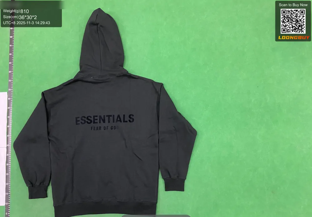 The back of a dark grey hooded sweatshirt laid flat on a green inspection bench, shoulders square to the camera