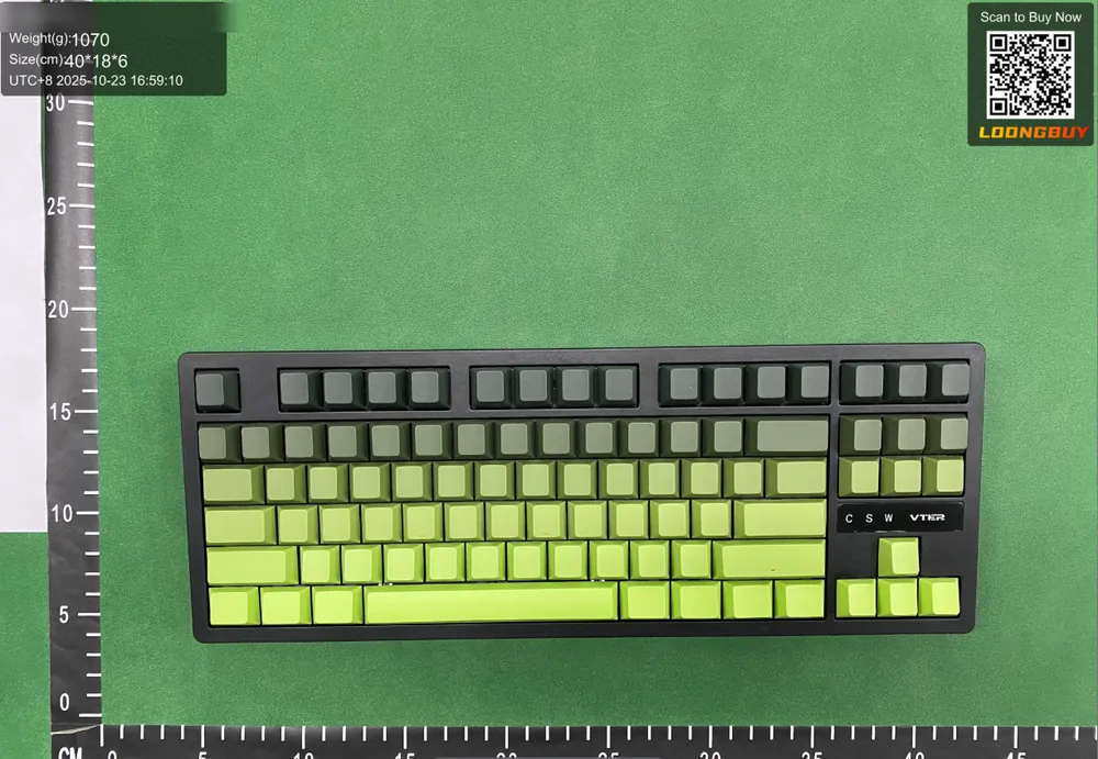 A mechanical keyboard laid flat on a green inspection bench with a centimetre ruler along the bottom edge and a data strip in the corner